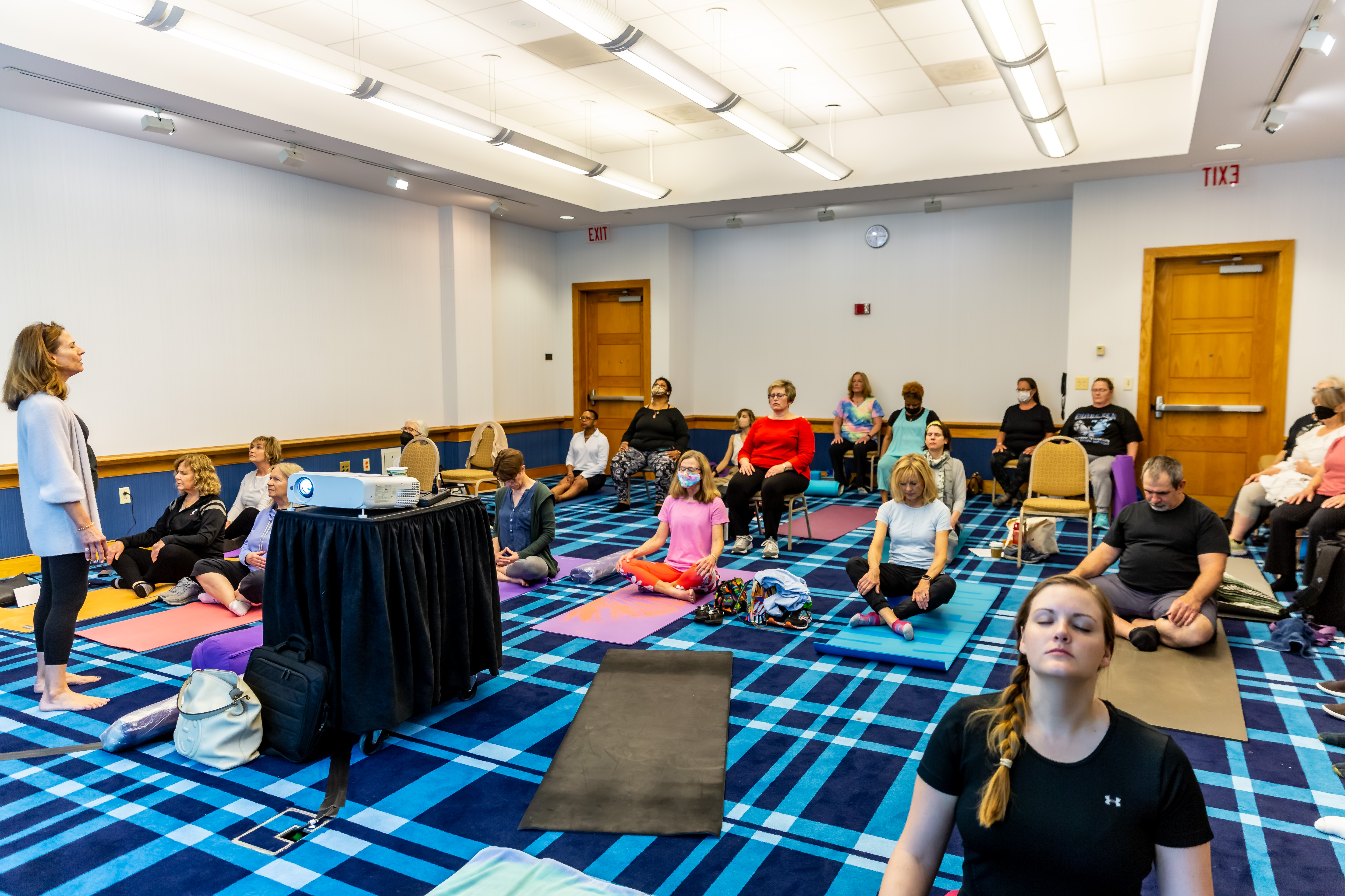 3UCCIHWSymposium22-3 group of people on yoga mats performing yoga